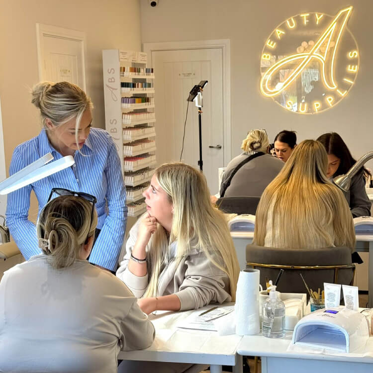 Beauty salon interior with clients receiving services and a neon sign in the background.