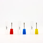 Four dental drill bits with colored plastic bases in red, blue, and yellow, displayed upright with their white protective cases on a clean white background.